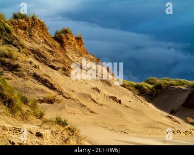 Sand dunes on the beach at Morfa Dyffryn between Barmouth and Harlech in Gwynedd on the north west coast of Wales with stormy sky above. Stock Photo