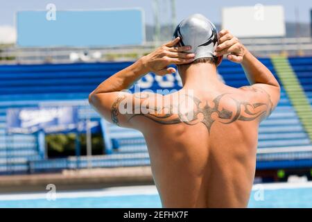 Rear view of a man with a tattoo on his back at the poolside Stock Photo