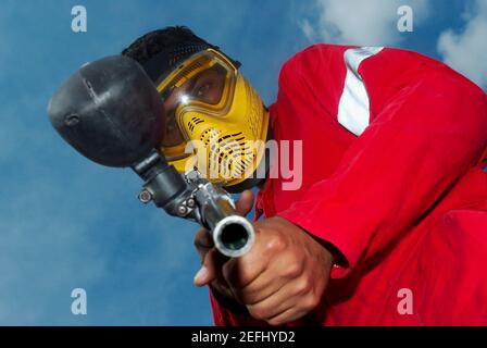 Low angle view of a mid adult man aiming with a paintball gun Stock Photo