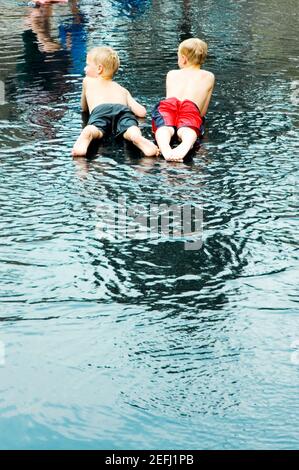Rear view of two boys lying down in water Stock Photo