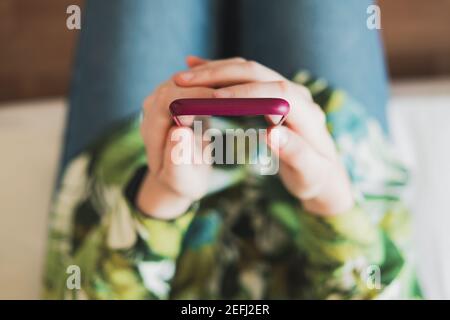 Mobile phone in woman's hands, shot from above with thin depth of field. Female person holding a smartphone in hands Stock Photo