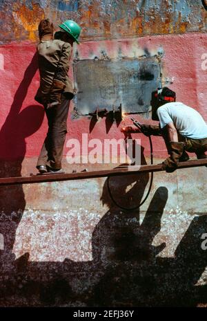 Low angle view of two men welding a tanker, Cebu, Philippines Stock Photo