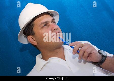 Close-up of a male construction worker holding a pen and thinking Stock Photo