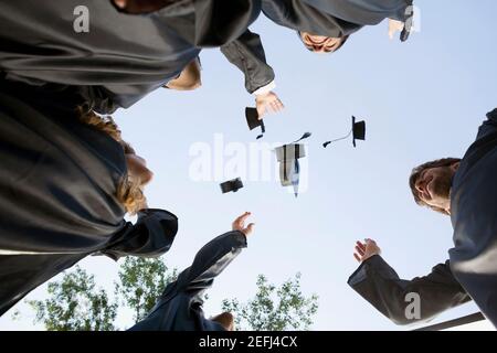 Low angle view of graduate students throwing their mortar boards in air Stock Photo
