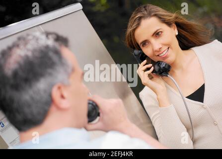 Close-up of a mid adult couple talking on a pay phone Stock Photo
