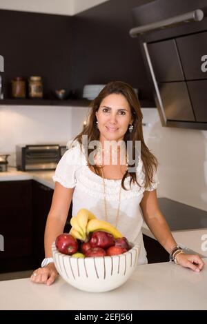 Portrait of a mid adult woman standing in front of a fruit bowl Stock Photo