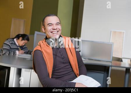 Portrait of a young man sitting in a computer lab and laughing Stock Photo