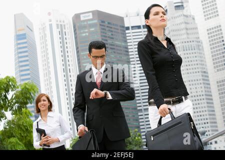 Two businesswomen and a businessman walking in front of buildings Stock Photo