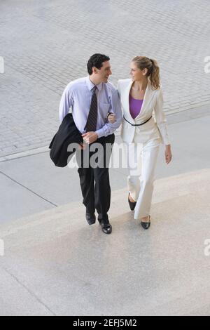 Businessman and a businesswoman moving up on steps with their arm in arm Stock Photo