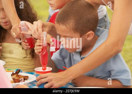 Two boys and a girl drinking from a cup Stock Photo