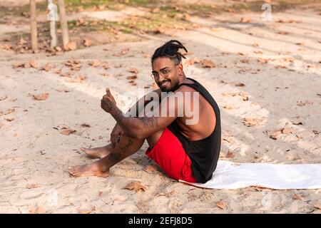 sports guy is sitting on a towel in a park, usually sand. he is african american Stock Photo