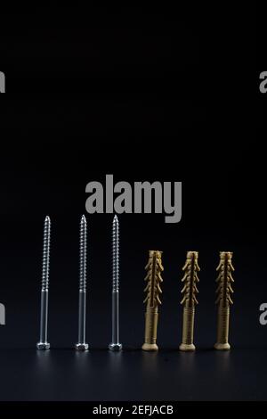 Plastic dowels with long metal self-tapping screw, on black background with copy space. Stock Photo