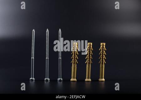 Long dowels with self-tapping screws on a black background with copyspace Stock Photo