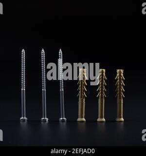 Long plastic dowels with self-tapping screws on a black background. Stock Photo