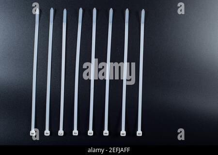 White plastic ties on black background. Cable ties close up on black. Stock Photo