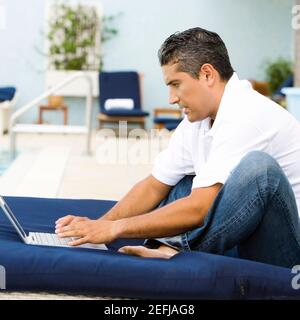 Side profile of a mid adult man using a laptop Stock Photo