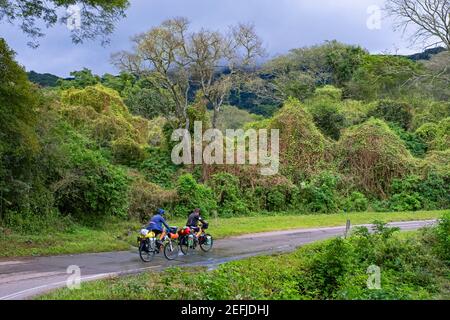 Two female touring cyclists riding heavily laden bicycles along the National Route 9 / Ruta Nacional 9, Salta-Jujuy section in Northern Argentina Stock Photo