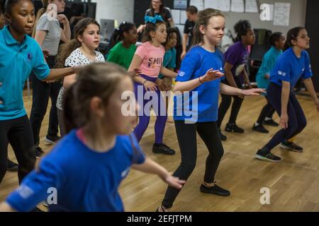 Schoolchildren participate in an indoor Physical Education (PE) lesson in a school in South East London, England, United Kingdom Stock Photo