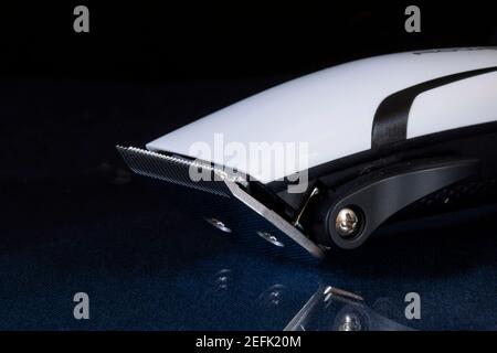 An electric razor for cutting hair is lying on a glass table. Equipment and tools on a black background Stock Photo