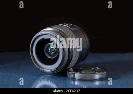 The black lens of the camera is lying on a glass table. Photographer's equipment on a black background Stock Photo