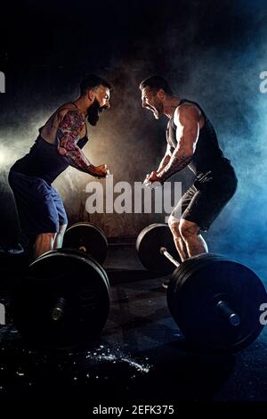 Two bearded tattooed muscular men look at each other and shout in the gym. Stock Photo
