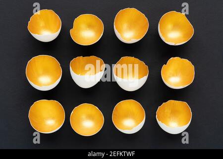 The concept of difference among equals. Golden eggshells are lined in rows on a black background. Creative design for Easter posters, cards, invitatio Stock Photo