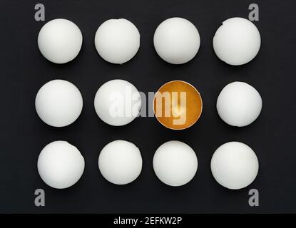 White and gold eggshell on a black background. The concept of difference among equals. Talent awakening concept. HR specialists search concept. The co Stock Photo
