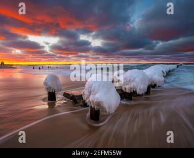 Beautiful winter sea landscape. Ice breakwaters, waves and fiery sunset. Artistic photography. Stock Photo