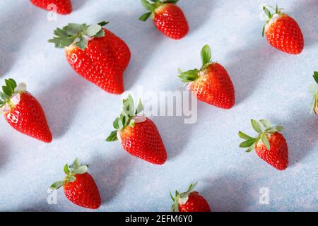 Pattern made of raw Red Organic Strawberries in a Bunch on blue background. Stock Photo