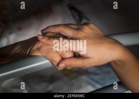 granddaughter holding the hand of her sick grandmother Stock Photo