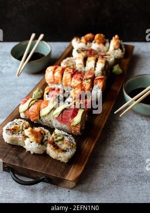 Close up of platter of assorted sushi rolls on gray cement background. Stock Photo