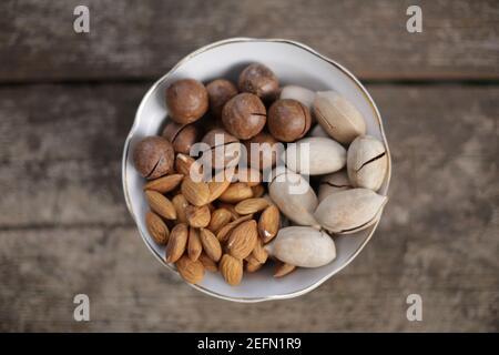 Mixed nuts in white plate on a wooden table Stock Photo