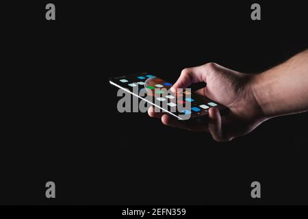 Male hand holding smartphone in black background Stock Photo