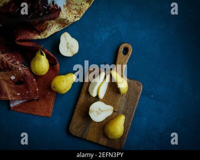 Fresh yellow pears on the wood cutting board with dish towel on the blue background , flat lay Stock Photo