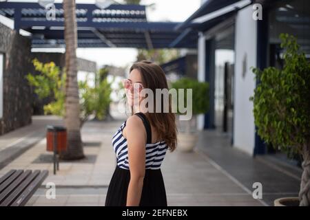 Attractive stylish caucasian girl is very happy and smiles because she is on vacation in an exotic location Stock Photo