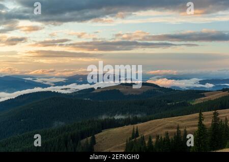 View of the mountain landscape from a height. Clouds and storm clouds in the mountains. Mountains and forests. Stock Photo