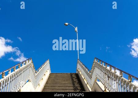 Old staircase with rusty railings leading up to a beautiful blue sky Stock Photo