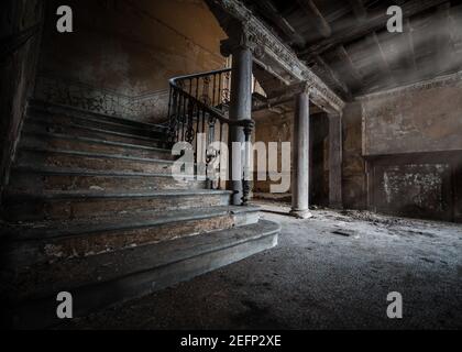 Dark creepy old basement with stone staircase leading to cellar underground light rays shining to make shadows on old stone tiled floor  and pillars Stock Photo