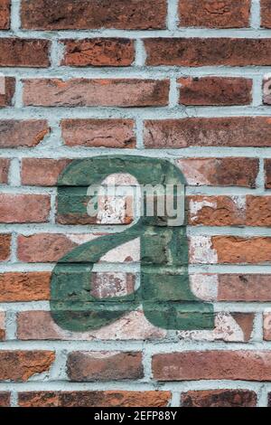 A green letter a painted on a red brick wall Stock Photo