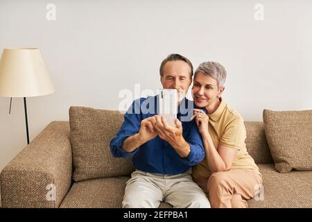 Senior couple in casuals at home sitting on couch Stock Photo
