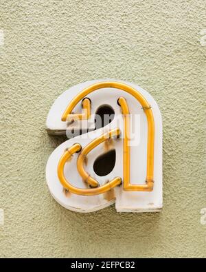 Yellow neon letter a on yellow-green wall Stock Photo