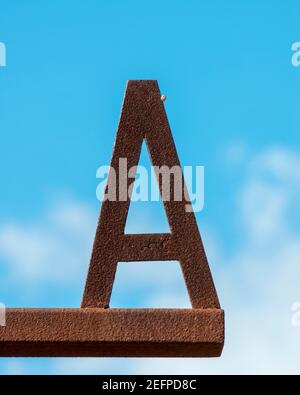 Rusty letter A with a little snail sitting on it against a blue sky Stock Photo