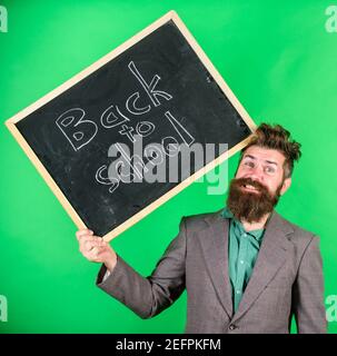 Teacher bearded man holds blackboard with inscription back to school green background. Keep working. Teaching stressful occupation. Teacher with tousled hair stressful about school year beginning. Stock Photo