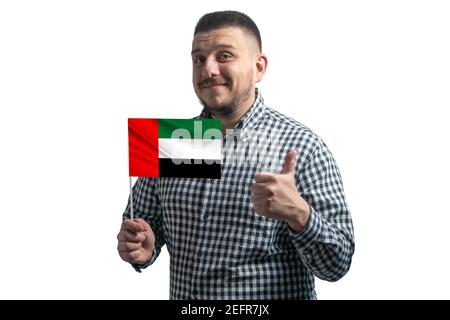 White guy holding a flag of United Arab Emirates and shows the class by hand isolated on a white background. Like for United Arab Emirates. Stock Photo