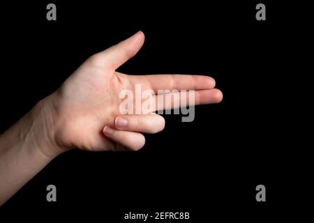 Person Holding symbolic gun with hand gesture, playing killing shooting weapons isolated on dark black background, symbolic gun concept Stock Photo