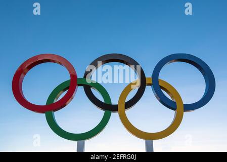 Five intertwined rings in blue, black, red, yellow and green on a blue background Stock Photo