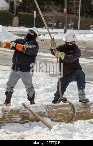 Detroit, Michigan, USA. 17th Feb, 2021. Working in bitterly cold weather, DTE Energy workers put up a new utility pole to provide electric service to an apartment building. Credit: Jim West/Alamy Live News Stock Photo
