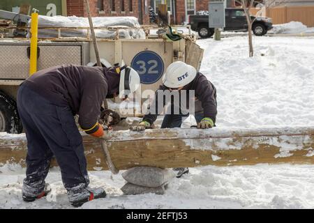 Detroit, Michigan, USA. 17th Feb, 2021. Working in bitterly cold weather, DTE Energy workers put up a new utility pole to provide electric service to an apartment building. Credit: Jim West/Alamy Live News Stock Photo