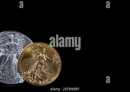 A one ounce gold coin and a one ounce silver eagle coin on a black background, with copy space Stock Photo