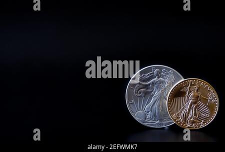 A one ounce gold and silver coin in the lower right corner of a black backdrop, with copy space Stock Photo